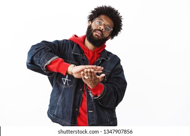 Indoor Shot Of Stylish And Arrogant African American Bearded Guy In Street-style Clothes Tilting Head As Sweep Money From Palm, Throwing Wad Of Cash At Camera With Snobbish Careless Expression