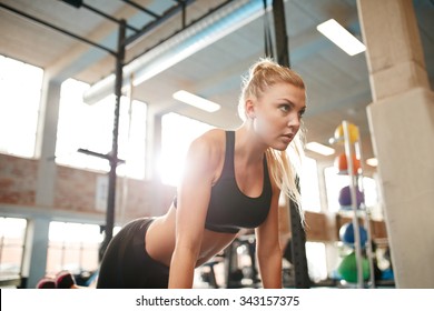 Indoor Shot Of Young Fitness Woman Doing Push Ups In Gym. Caucasian Female Working Out In Health Club.