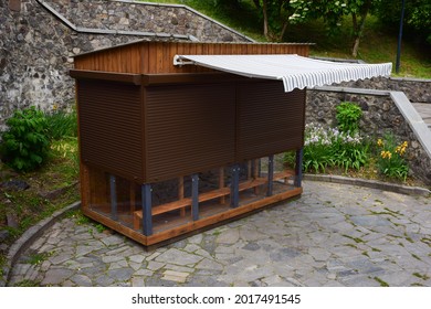 Indoor Small Wooden Trade Shop With An Awning. The Windows Are Closed With Roller Shutters. No People