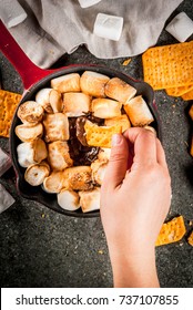 Indoor Smores, Baked Smores Dip In A Cast Iron Skillet Pan With Graham Crackers. Girls Hand In Picture, Tasting Smores, Dark Grey Table, Top View Copy Space