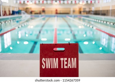 Indoor Swimming Pool With A Sign.  Pool Is Empty, Calm Water Surface.  Lap Lines In.