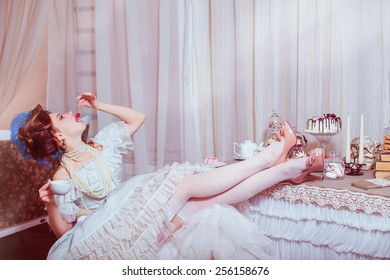 Indoors shot in the Marie Antoinette style. Woman eating red cherry.