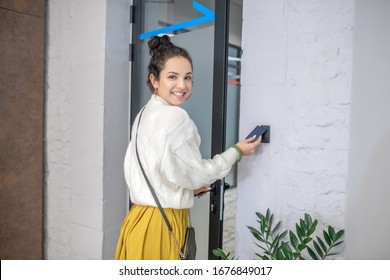 Indoors. Young Woman Leaving, Holding Access Card To Unclock The Door, Smiling