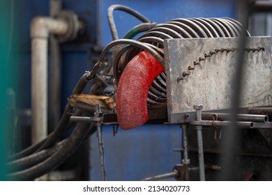 Induction, crucible melting furnace. A red-hot metal pipe takes the form of a half-branch under the influence of heat in an induction furnace