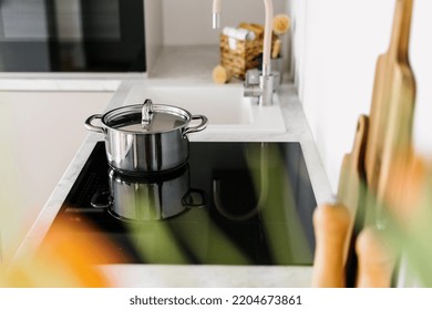 An Induction Hob Built-in The Countertop. Glass Ceramic Stove With Shiny Metal Pot On Top. Concept Of Cooking Homemade Healthy Food On Professional Kitchen. Household Appliance And Domestic Life