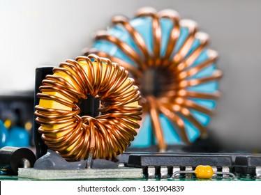 Inductors detail. Copper wire winding. Magnetic ferrite core. Inverter. Beautiful colored coils in dismantled electric power supply unit. Colorful electronic parts. Chips, capacitor. Selective focus.