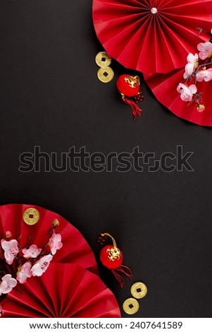 Indulging in the exuberance of the Chinese New Year festival. Top view vertical photo of folding fans, sakura, traditional coins, lanterns on black background with promo spot