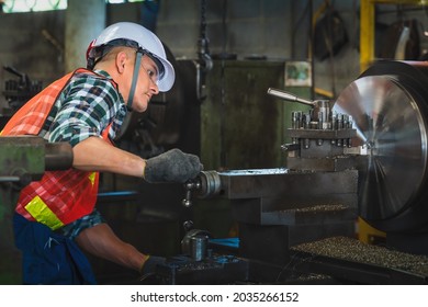 Industrail background of portrait of mechanic engineer operating lathe machine to make metal part in metalwork workshop and factory