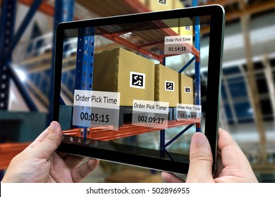 Industrial 4.0 , Augmented Reality And Smart Logistic Concept. Hand Holding Tablet With AR Application For Check Order Pick Time In Smart Factory Background