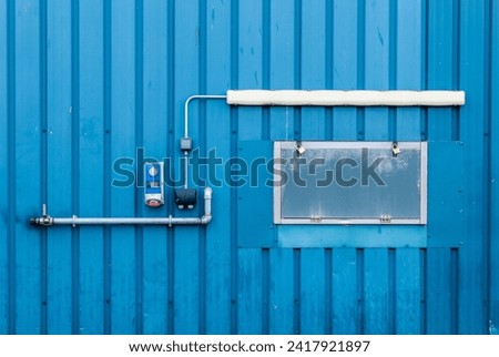 Industrial abstract blue corrugated metal wall with pipes, wires and dials