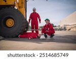 Industrial accident scene worker in lying on the ground near a large tire of a heavy-duty vehicle one worker used radio communication to emergency center to help friend is industrial safety worksite.