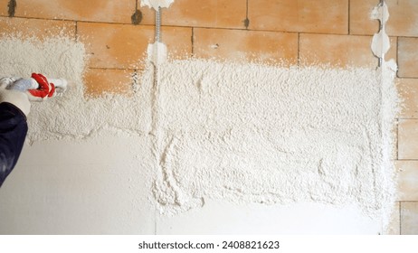 Industrial application of solution to the wall through a hose. Applying putty using a machine. Plasterers use and operate mortar spraying equipment, mortar spraying machine.