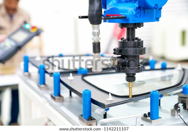 Industrial automated robot arm holding car glass\
in factory