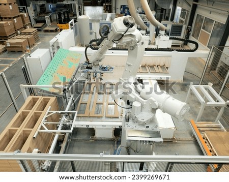 Industrial automation and robotics in modern industrial factory. High precision robotic arm assembling wooden furniture in big furniture manufacturing facility with industrial robotic manipulators.