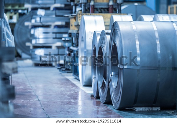 Industrial background. Big size steel\
coil stored inside industrial warehouse, blue toned\
image.