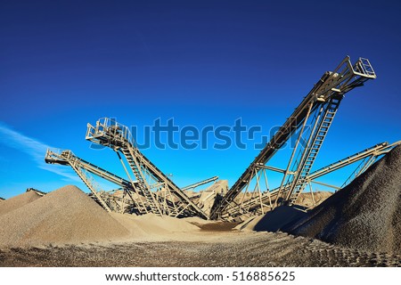 Industrial background with gravel crusher. Extraction of gravel. Conveyor for transporting gravel. Morning. Beautiful light.