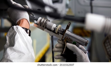 Industrial Background With The Process Of Painting The Car Frame. Scene. Close Up Side View Of The Worker Hand With A Paint Spray At The Production Of Cars.