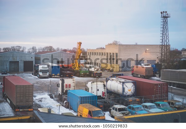 Industrial\
backyard with trailers, crane and\
trucks.
