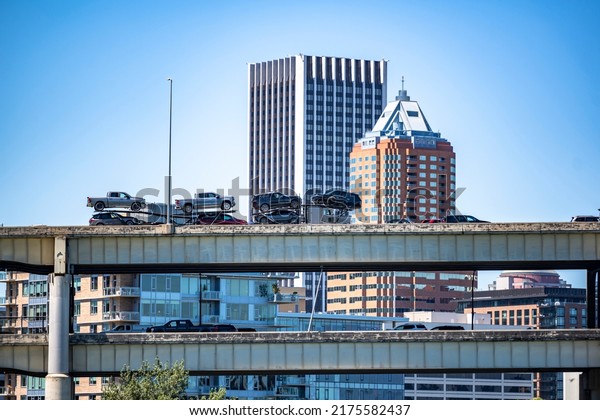 Industrial Big rig car hauler semi truck\
transporting cars on the modular semi trailer running on the upper\
level of two level transportation bridge across the Willamette\
River in Down Town\
Portland