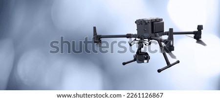 Industrial black drone with camera on a blurred gray background
