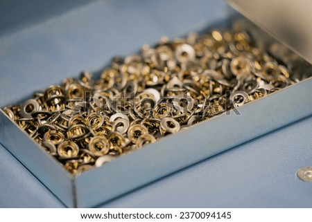 Industrial boxes full of stainless steel work clothing rivets