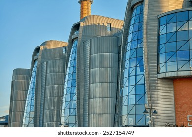 Industrial building with futuristic design. Factory exterior with curved metallic facades and large glass windows. Modern architecture and innovation concept - Powered by Shutterstock