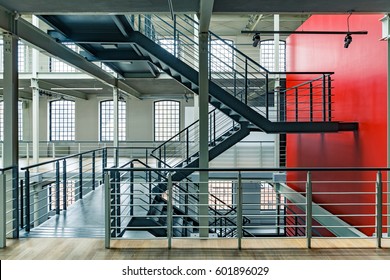 Industrial building interior with red wall and black, metal staircase - Powered by Shutterstock