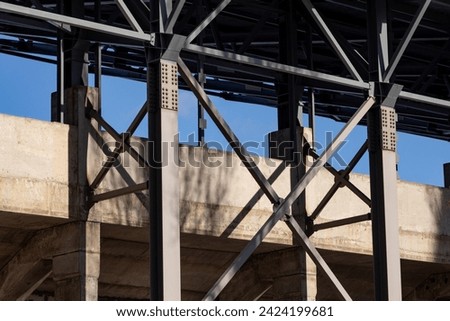 Industrial building, metal structures. Concrete pillars with bolted connections of metal support structures and roof of industrial building.