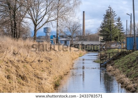 An industrial canal on the site of a former steel mill under a slightly cloudy January sky.The area of the former large closed complex (plant) - steelworks. Grayish January nature waiting for spring .
