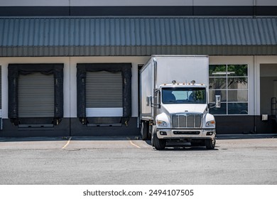 Industrial carrier white big rig day cab semi truck tractor with dry van semi trailer loading commercial cargo for next freight  standing in warehouse dock gate - Powered by Shutterstock