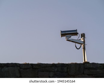 Industrial CCTV camera in solid metal enclosure. Security camera against blue sky. Outdoor surveillance equipment