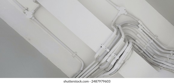 Industrial ceiling background with white cable conduit pipes. Exposed ceiling, industrial design, cable management, modern architecture, urban infrastructure. - Powered by Shutterstock