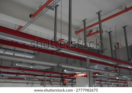 Industrial ceiling infrastructure with complex pipework and rails.