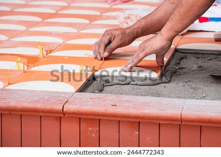 industrial ceramic  builder worker installing floor tile at repair renovation work - Handyman installing ceramic tiles - A special cement mass to fill gaps between the laid ceramics.