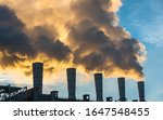 Industrial chimneys spewing smoke and soot in the blue sky polluting the air and causing global warming and climate change with greenhouse gasses and CO2 emissions