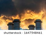 Industrial chimneys spewing smoke and soot in the blue sky polluting the air and causing global warming and climate change with greenhouse gasses and CO2 emissions