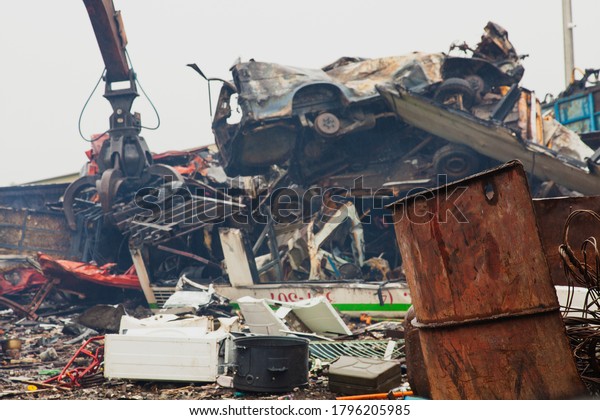 Industrial claw machine,\
move scrap metal in the landfill. Excavator arm, scrap metal base\
with old cars.