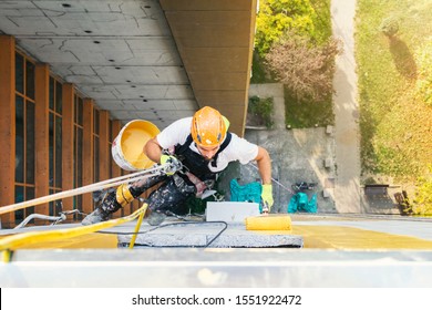 Industrial Climber Hanging On The Rope While Painting The Exterior Facade Wall Of The Tall Apartment Building. Industrial Alpinism Concept Image