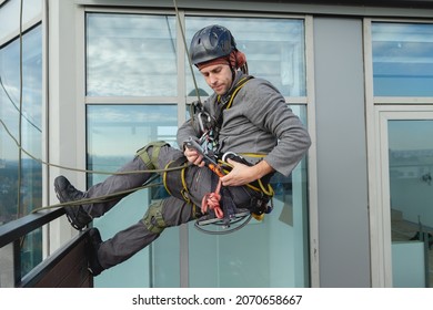 Industrial climber is preparing to hang out from the balcony of the building. Preparation for high-altitude work