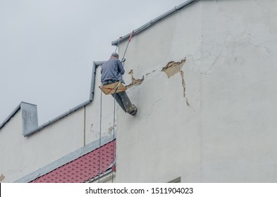 Industrial Climber Seals Cracks In The Wall Of A Multi-storey Building Outside