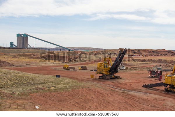 Industrial coal mining equipment\
and silos beside a row of railway cars in a Wyoming valley\
landscape