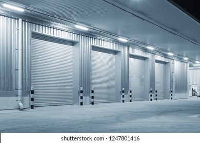 Industrial Or Commercial Building Exterior. Use As Factory, Warehouse, Store And Workplace. Safety And Protection With Roller Door, Roller Shutter Or Overhead Door. Concrete Pavement Floor Outside.