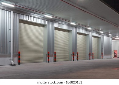 Industrial Or Commercial Building Exterior. Use As Factory, Warehouse, Store And Workplace. Safety And Protection With Roller Door, Roller Shutter Or Overhead Door. Concrete Pavement Floor Outside.