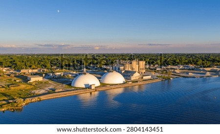 Industrial complex with storage domes and grain silos situated by a peaceful waterfront of Saginaw river
