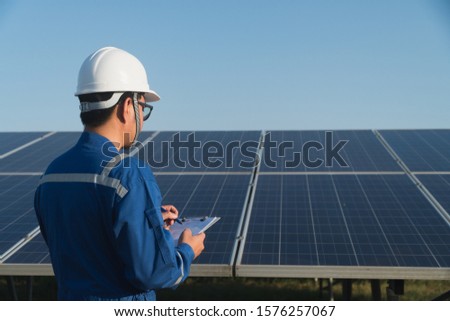 industrial concept; engineer in blue uniform working on repairing generating power of solar power plant 
