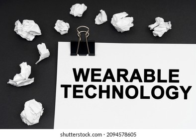 Industrial Concept. On A Black Background, There Are Crumpled Pieces Of Paper And Paper With The Inscription - Wearable Technology