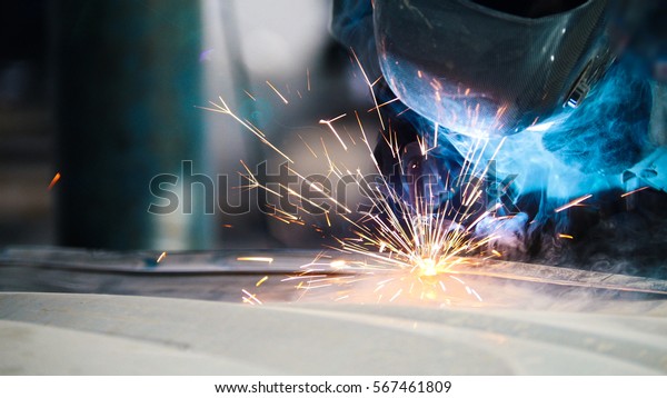 Industrial concept: worker in helmet repair\
detail in car auto service, close\
uptelephoto