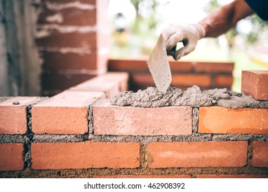 Industrial Construction Bricklayer Worker Building Walls With Bricks, Mortar And Putty Knife
