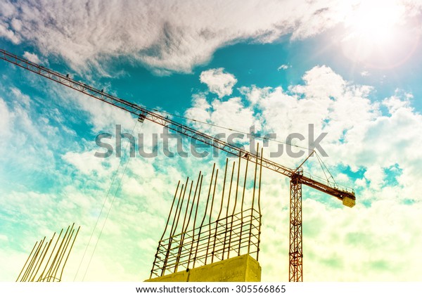 Industrial construction crane\
building skyscrapers and houses. Crane silhouette on construction\
site, industrial tools closeup. Soft, vintage effect on\
photo