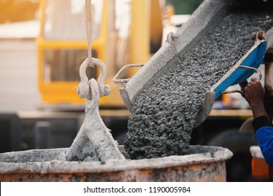 Industrial construction machinery workers pouring cement concrete using a concrete bucket